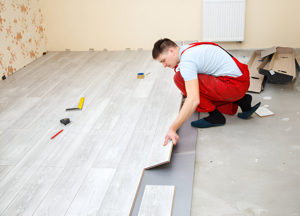 Worker installing wooden flooring in a multi-unit apartment space